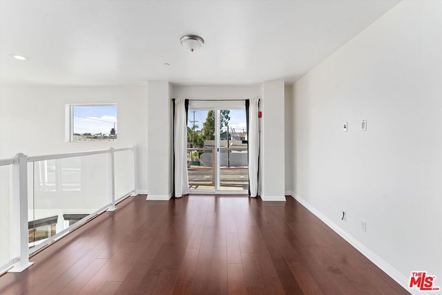 empty room with plenty of natural light and dark hardwood / wood-style flooring