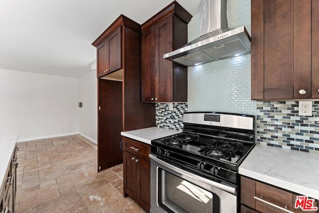 kitchen featuring backsplash, wall chimney exhaust hood, stainless steel gas range, and light stone counters