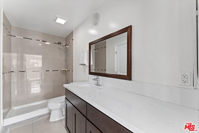 bathroom with toilet, vanity, tile patterned floors, and tiled shower