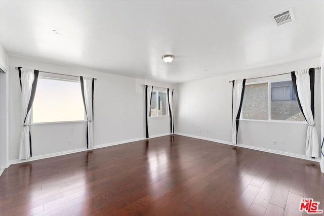 empty room featuring a healthy amount of sunlight and dark hardwood / wood-style floors