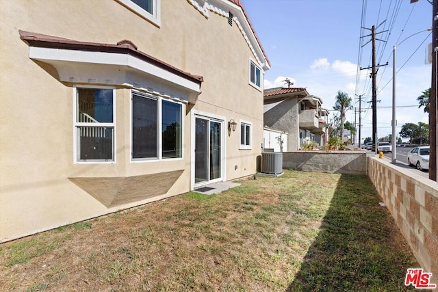 back of property featuring cooling unit and a lawn