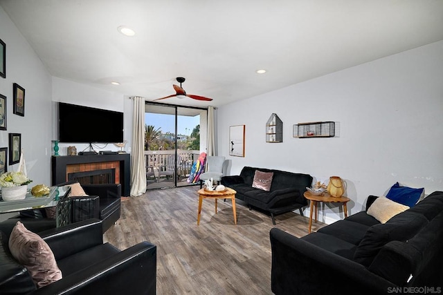 living room with hardwood / wood-style flooring, ceiling fan, and a wall of windows