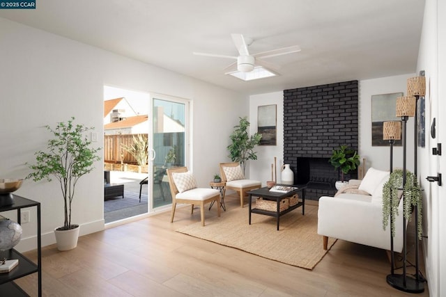 living area featuring ceiling fan, a fireplace, and wood-type flooring