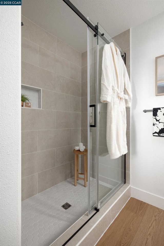 bathroom featuring wood-type flooring, a textured ceiling, and walk in shower