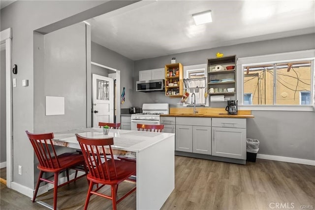 kitchen featuring wood counters, gas range gas stove, light hardwood / wood-style floors, white cabinets, and sink