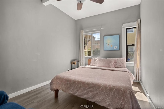 bedroom featuring ceiling fan, hardwood / wood-style flooring, and lofted ceiling with beams