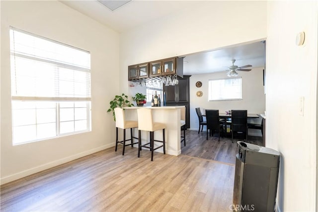 kitchen with ceiling fan, hardwood / wood-style floors, a kitchen bar, and kitchen peninsula