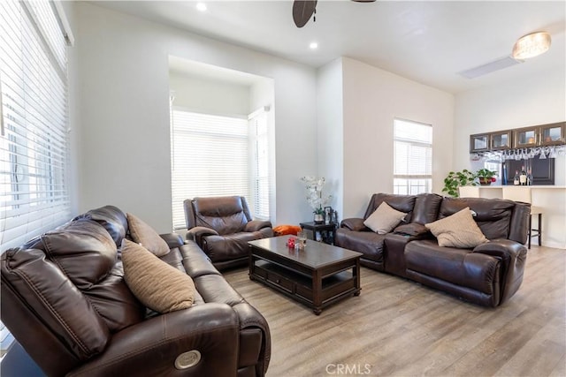 living room featuring light wood-type flooring, ceiling fan, and plenty of natural light