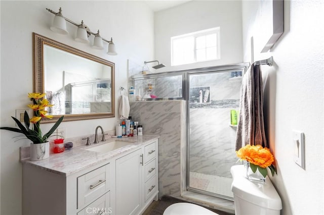 bathroom with a shower with door, toilet, and vanity