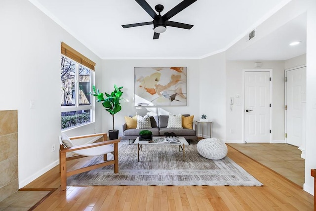 living area featuring wood-type flooring, ceiling fan, and crown molding