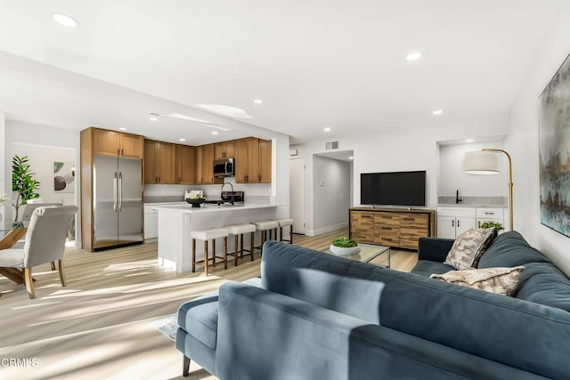 living room featuring sink and light hardwood / wood-style flooring