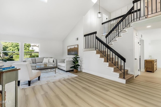 living room featuring high vaulted ceiling and light hardwood / wood-style floors