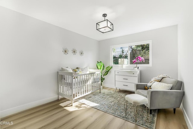 bedroom featuring a crib and light hardwood / wood-style floors