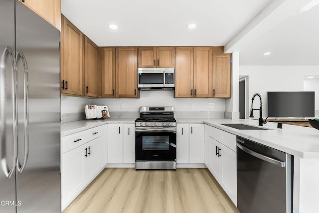 kitchen featuring light hardwood / wood-style floors, stainless steel appliances, white cabinets, light stone counters, and sink