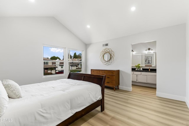 bedroom featuring ensuite bathroom, lofted ceiling, and light hardwood / wood-style floors