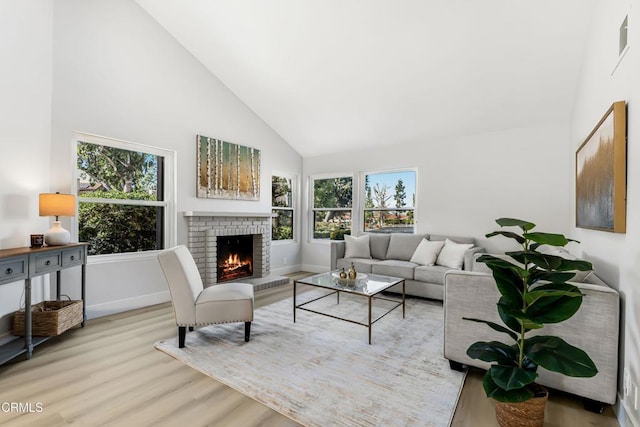 living room featuring high vaulted ceiling, light hardwood / wood-style floors, and a fireplace