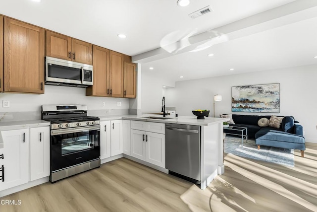 kitchen featuring sink, white cabinets, kitchen peninsula, and appliances with stainless steel finishes