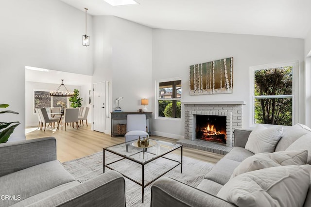 living room featuring a skylight, a fireplace, hardwood / wood-style floors, and high vaulted ceiling