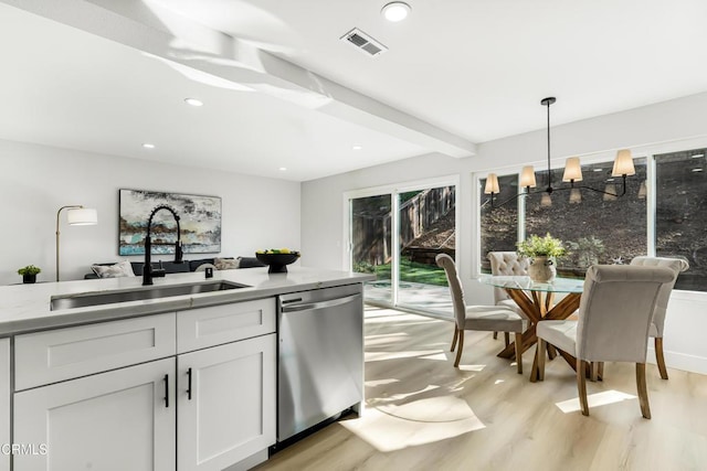 kitchen featuring light wood-type flooring, hanging light fixtures, stainless steel dishwasher, white cabinets, and sink