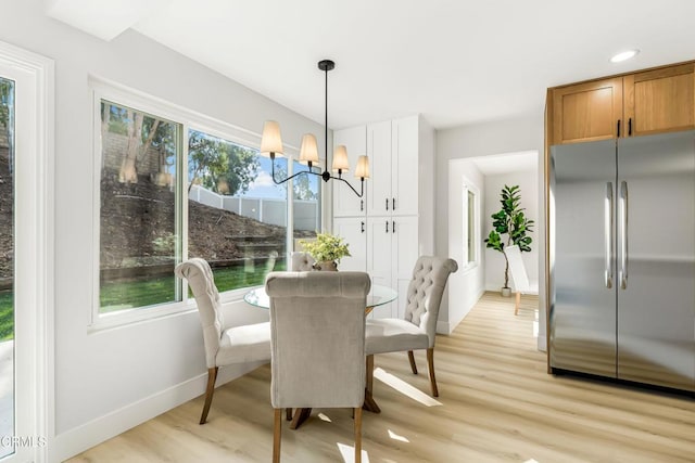 dining area with light wood-type flooring and an inviting chandelier