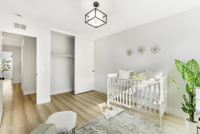 bedroom with a closet, a nursery area, and light hardwood / wood-style flooring