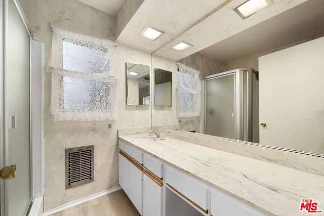 bathroom with a shower with shower door, vanity, and wood-type flooring