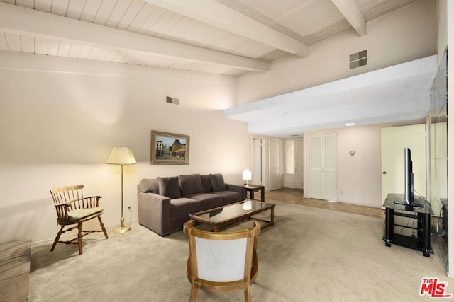 carpeted living room featuring beamed ceiling