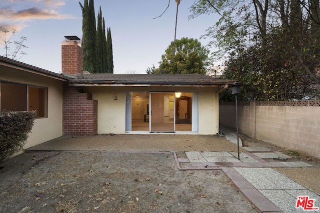 back house at dusk with a patio area