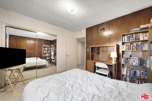 bedroom featuring light colored carpet, a closet, and wood walls