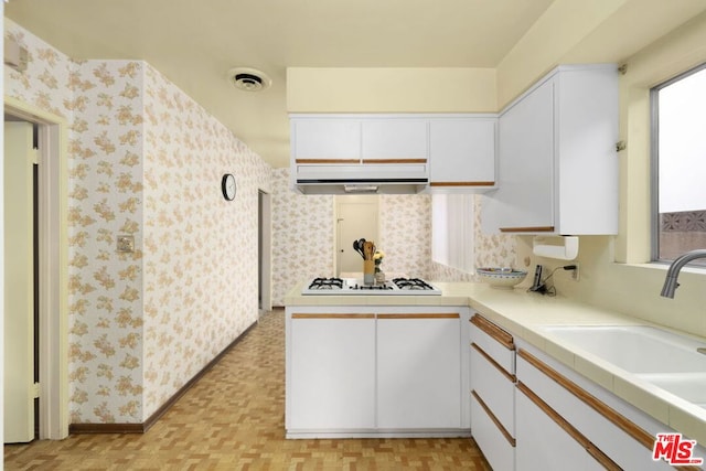 kitchen with white gas cooktop, light parquet floors, sink, and white cabinetry