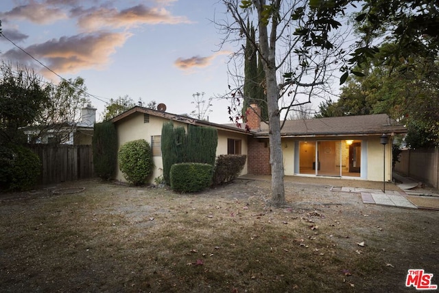 back house at dusk with a lawn