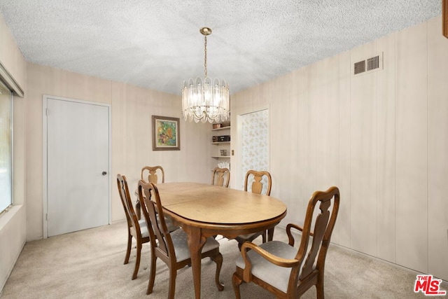 dining space featuring a textured ceiling, light colored carpet, and a notable chandelier