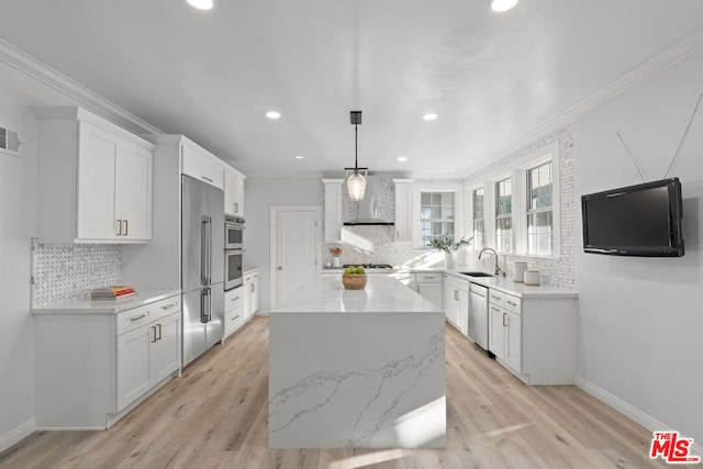 kitchen featuring white cabinetry, appliances with stainless steel finishes, pendant lighting, light stone counters, and a center island