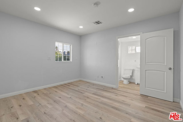 unfurnished bedroom with ensuite bathroom and light hardwood / wood-style flooring