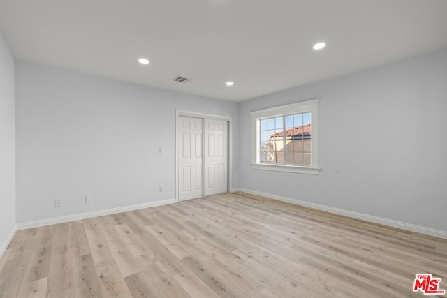 unfurnished bedroom featuring a closet and light wood-type flooring