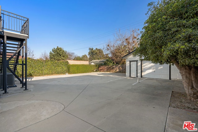 view of patio / terrace with a garage, central AC unit, and an outdoor structure