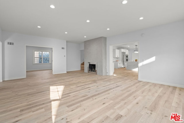 unfurnished living room with light wood-type flooring and a fireplace