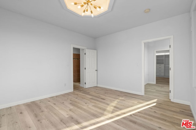 empty room with an inviting chandelier and light hardwood / wood-style flooring