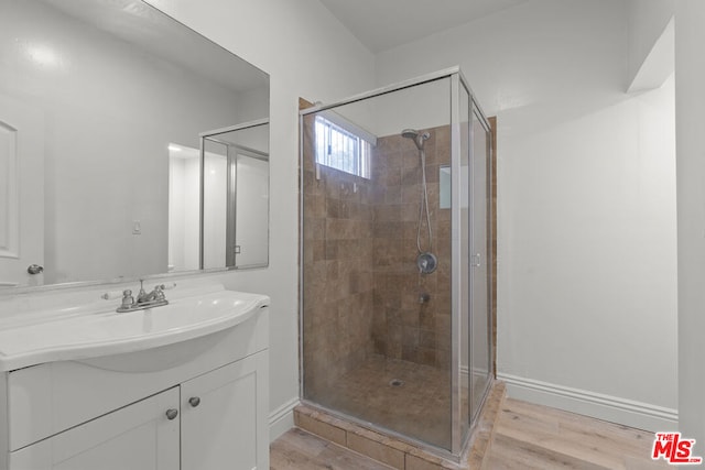 bathroom with a shower with shower door, hardwood / wood-style floors, and vanity