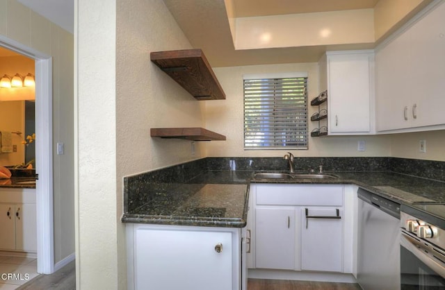 kitchen with dishwasher, sink, white cabinetry, and dark stone counters