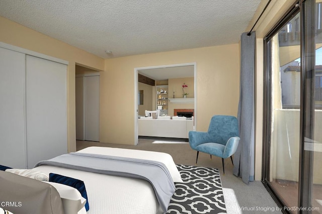 carpeted bedroom with a textured ceiling, a closet, and a fireplace