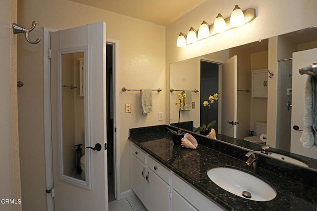 bathroom featuring toilet, tile patterned flooring, walk in shower, and vanity