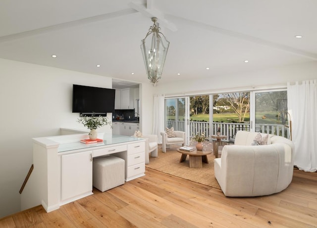 living room featuring light hardwood / wood-style floors, beam ceiling, and an inviting chandelier