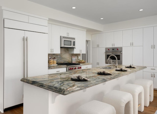 kitchen featuring sink, white cabinets, a large island, and appliances with stainless steel finishes