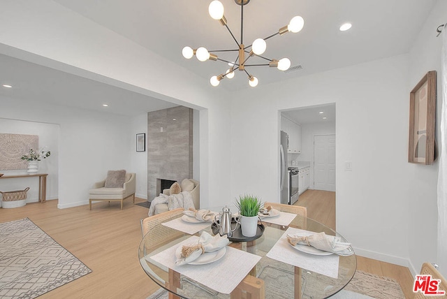 dining area featuring a fireplace, a chandelier, and light hardwood / wood-style flooring