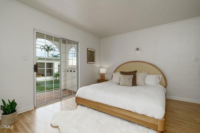 bedroom featuring ornamental molding, wood-type flooring, and access to exterior