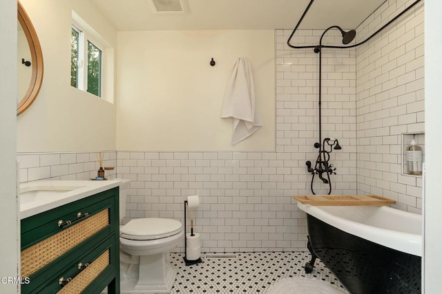 bathroom with tile patterned floors, toilet, tile walls, and vanity