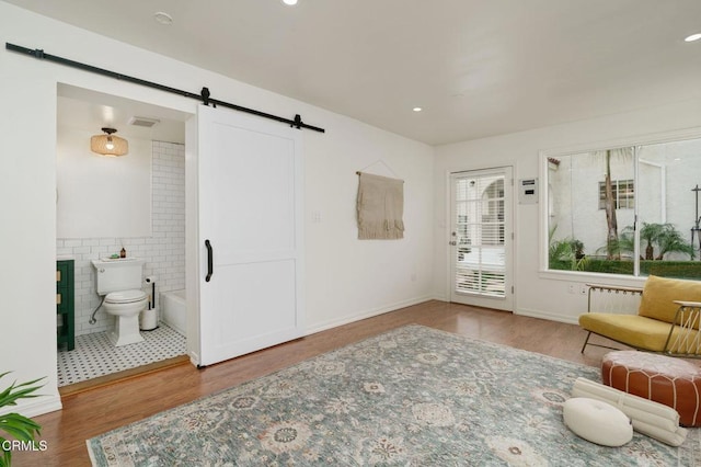 interior space featuring a barn door, hardwood / wood-style floors, and tile walls