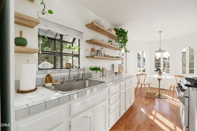 kitchen featuring high end range, tile countertops, sink, and white cabinets