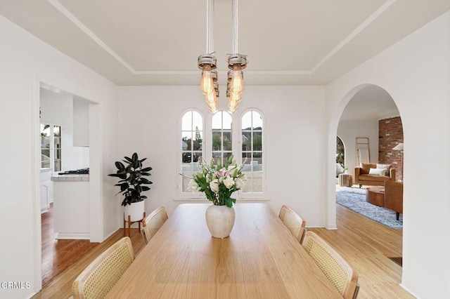 dining space featuring a raised ceiling, a notable chandelier, and light hardwood / wood-style flooring